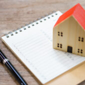 Image of a toy house on a notepad with a pen representing home maintenance reminders