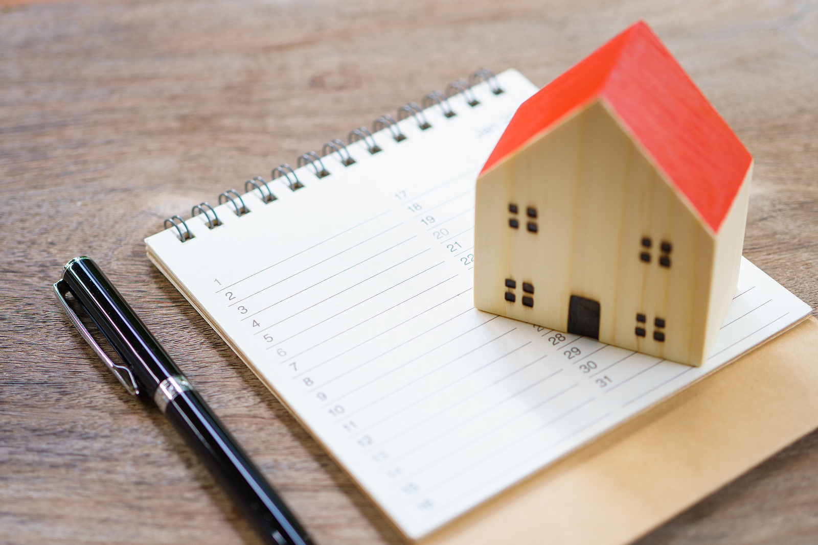 Image of a toy house on a notepad with a pen representing home maintenance reminders