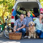 Family in front of car packed for road trip