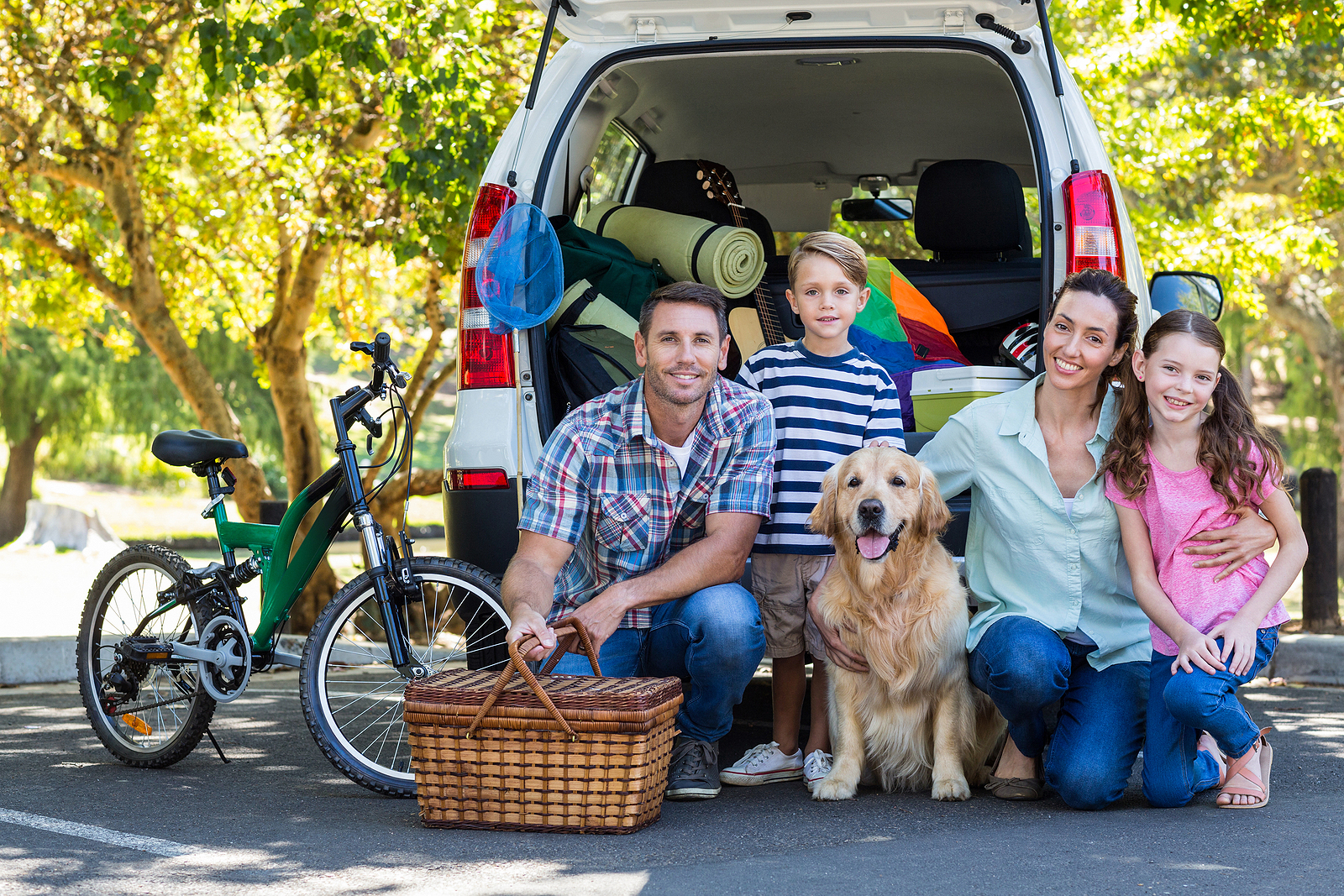 Family in front of car packed for road trip