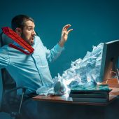 Man in front of laptop can't defend against spam email appearing to blast out at him